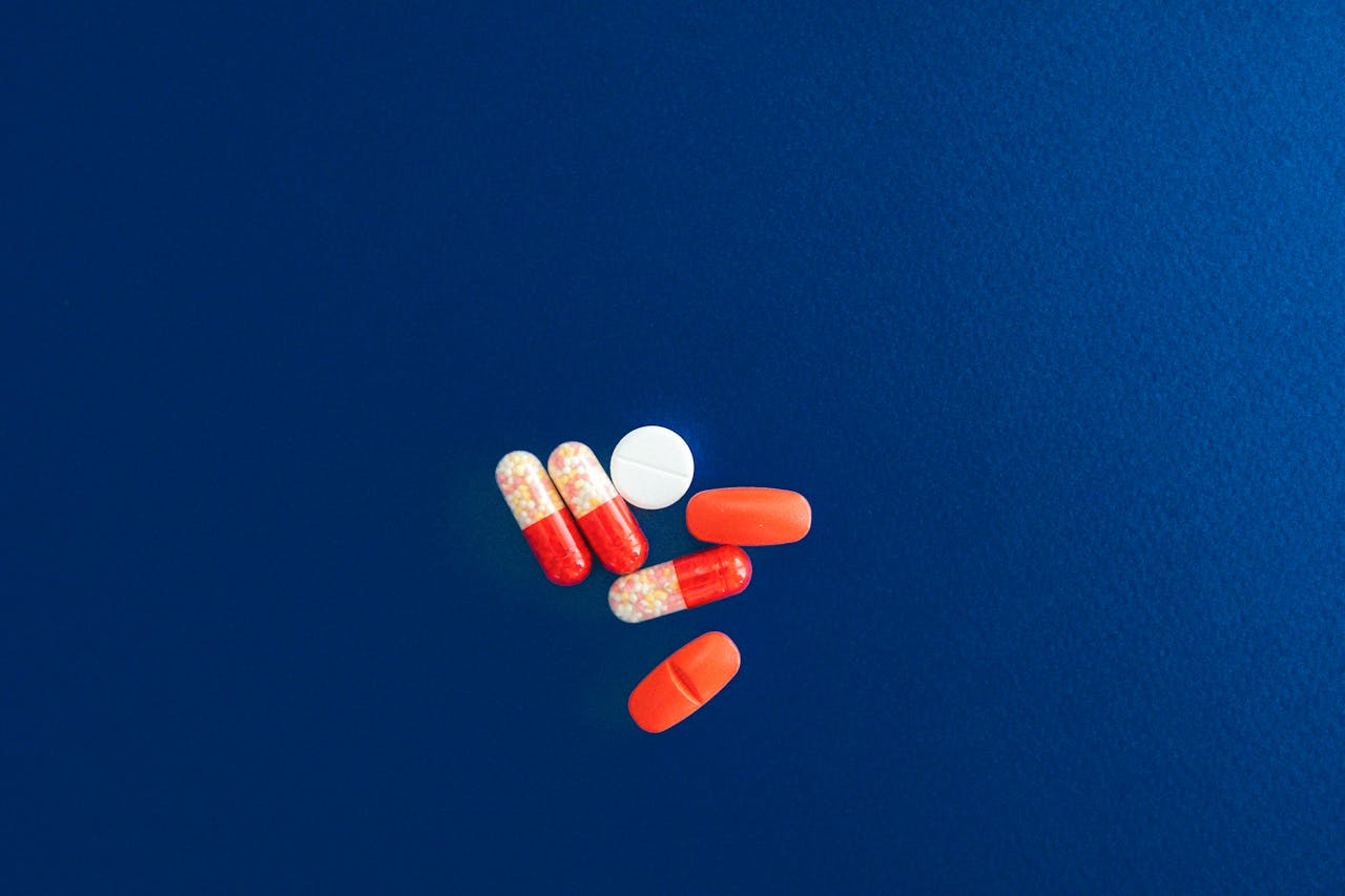 our-services-2 Assorted red and white capsules and tablets on a vivid blue surface.
